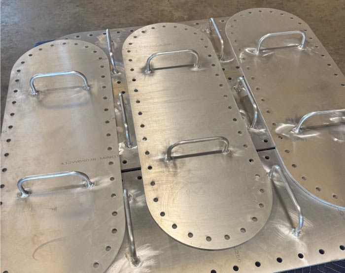 Custom fabricated aluminum access covers featuring heavy-duty welded handles and precision-drilled bolt holes, demonstrating RAW Welding's expertise in industrial welding and custom metal fabrication solutions.