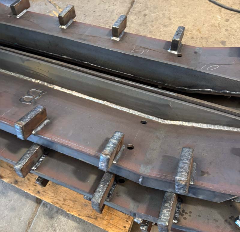 Close-up view of a heavy-duty fabricated metal component featuring thick steel plates welded together with multiple reinforcement brackets and visible, high-quality weld beads