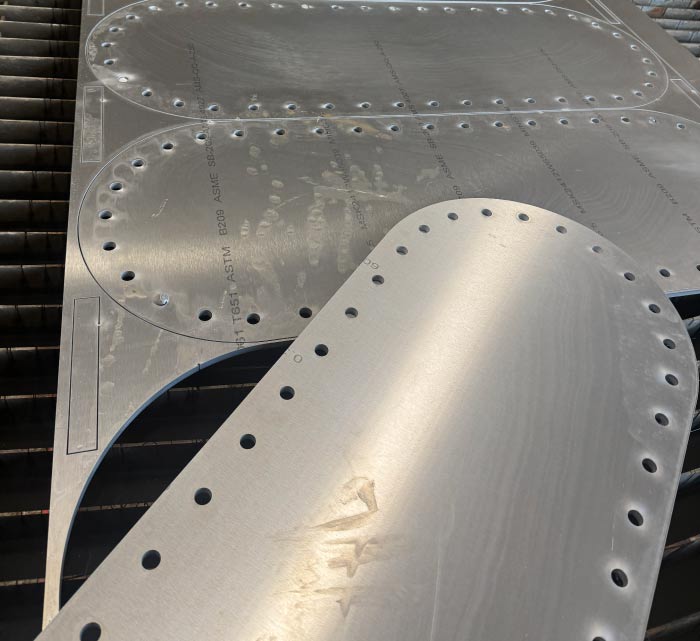 Finished fabricated metal components resting on the parent sheet after cutting, highlighting the smooth edges, tight tolerances, and material efficiency achieved through RAW Welding's advanced water jet fabrication services.