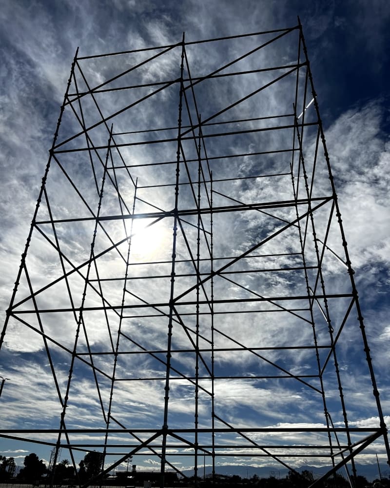 Tall metal industrial scaffolding tower structure erected against a blue sky to provide safe vertical access for construction and maintenance crews