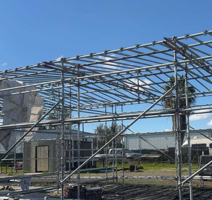 Outdoor construction site featuring a complex network of galvanized steel scaffolding pipes and connectors assembled for a new building metal installation project.