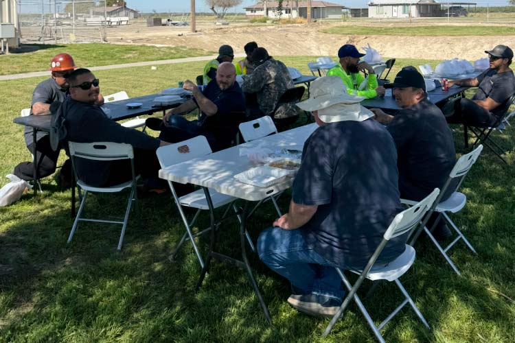 The RAW Welding team enjoying a group meal outdoors at white folding tables during a break. This candid shot highlights the company’s family values, supportive environment, and the strong camaraderie among the skilled tradespeople.